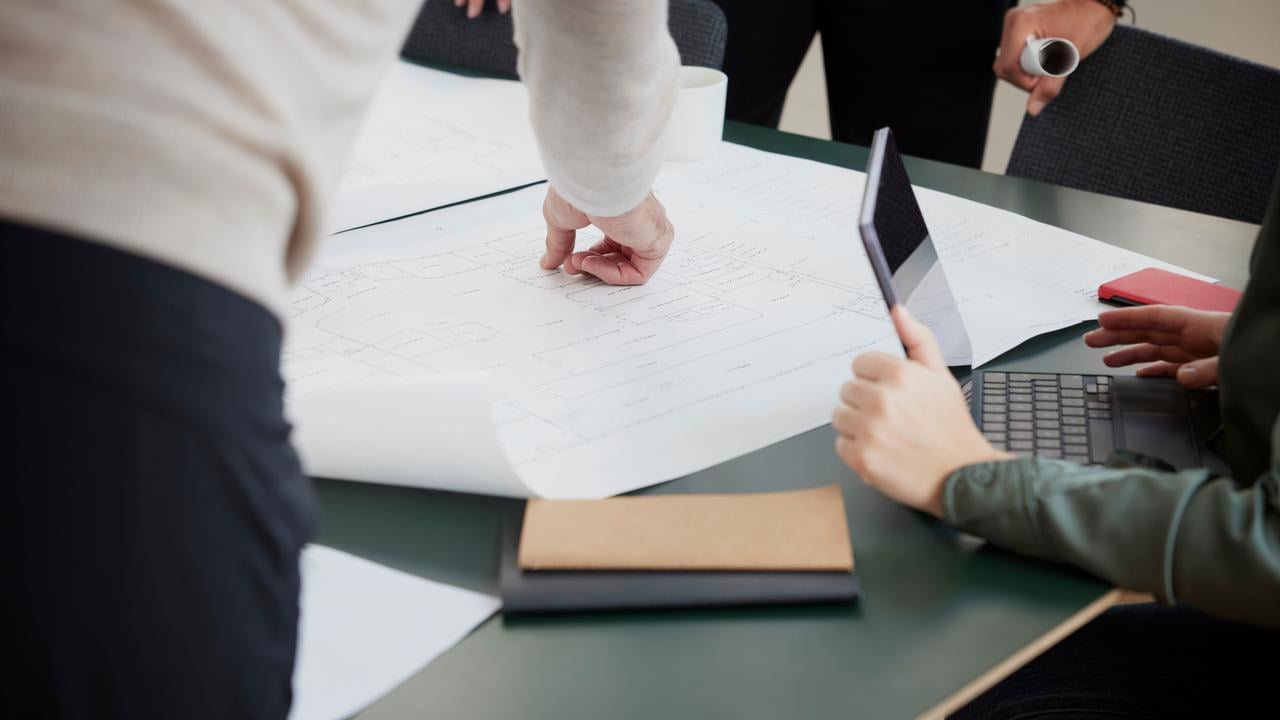 Bild p&aring; personer som tittar p&aring; en ritning p&aring; ett bord