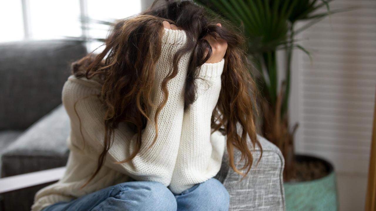 Kvinna som döljer sitt ansikte i sina händer. Ska illustrera psykisk ohälsa, depression, nedstämdhet eller liknande.