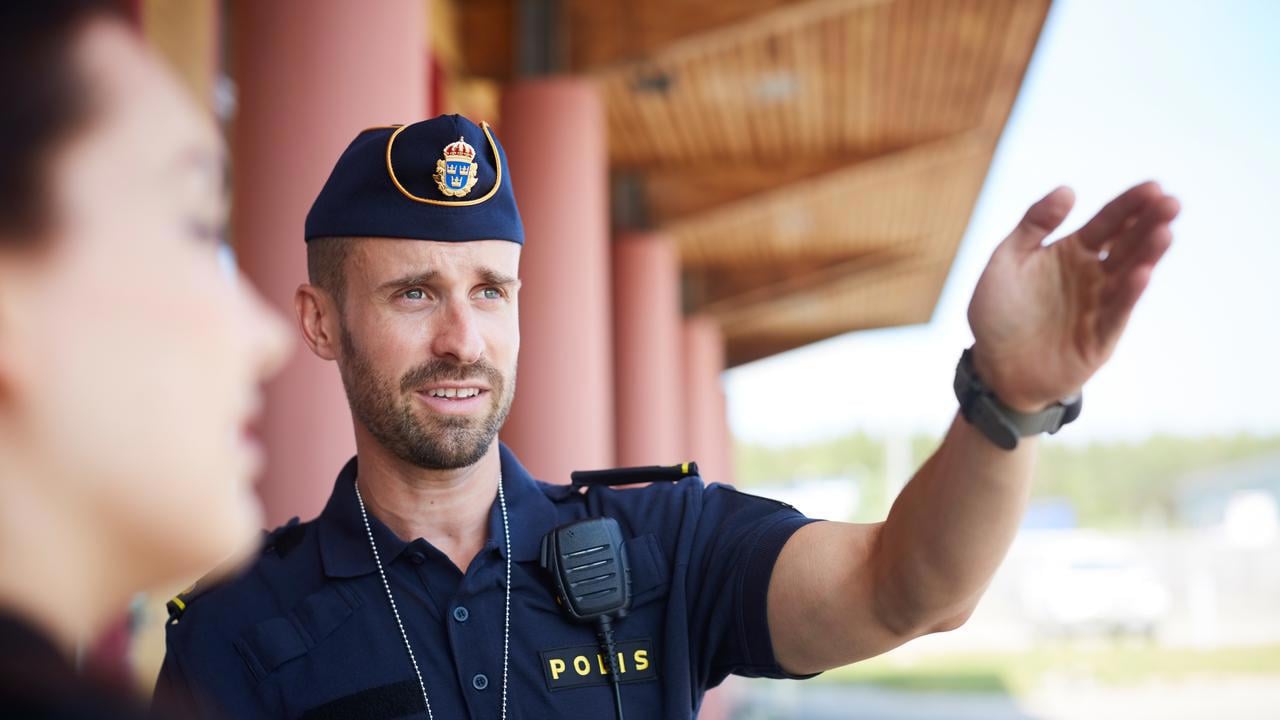 Manlig polis visar vägen med handen.