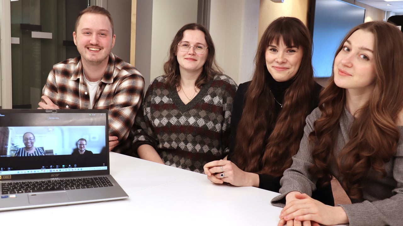 Fyra sitter p&aring; rad vid bord, tv&aring; p&aring; datorsk&auml;rm