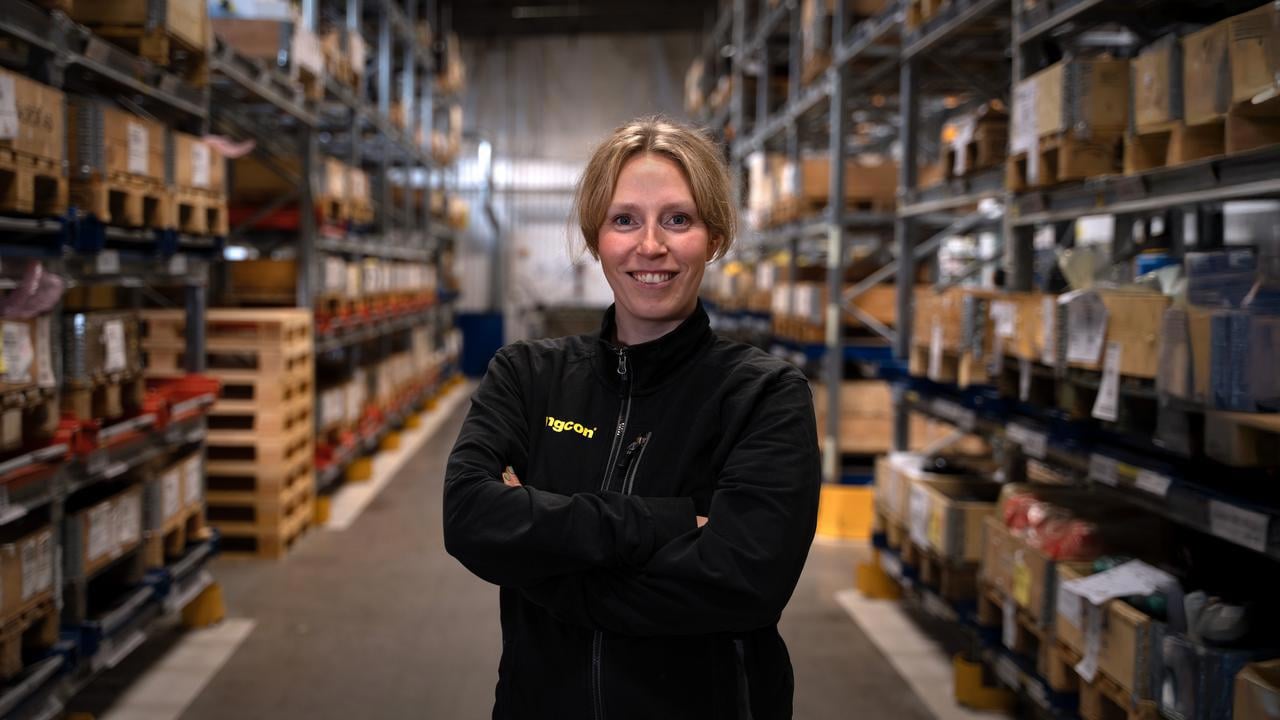 En kvinna som st&aring;r i en lagerlokal med m&aring;nga hyllor.