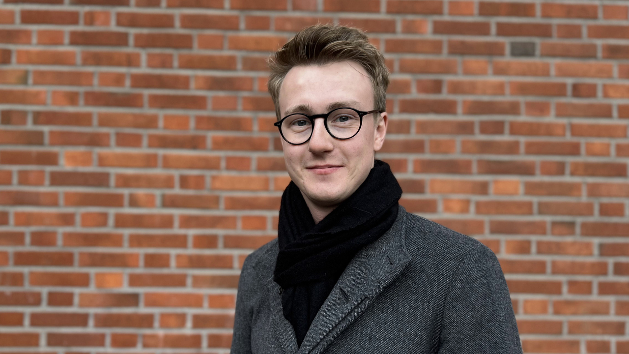 Doktorand Oliver Larsson i kort h&aring;r och glas&ouml;gon, ikl&auml;dd varm kappa, utomhus.