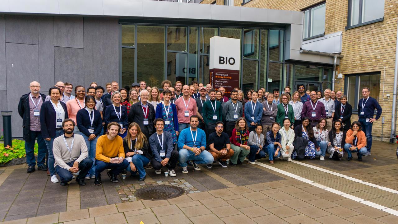En stor grupp symposiumdeltagare poserar tillsammans utanf&ouml;r Biologihuset vid Ume&aring; universitet.