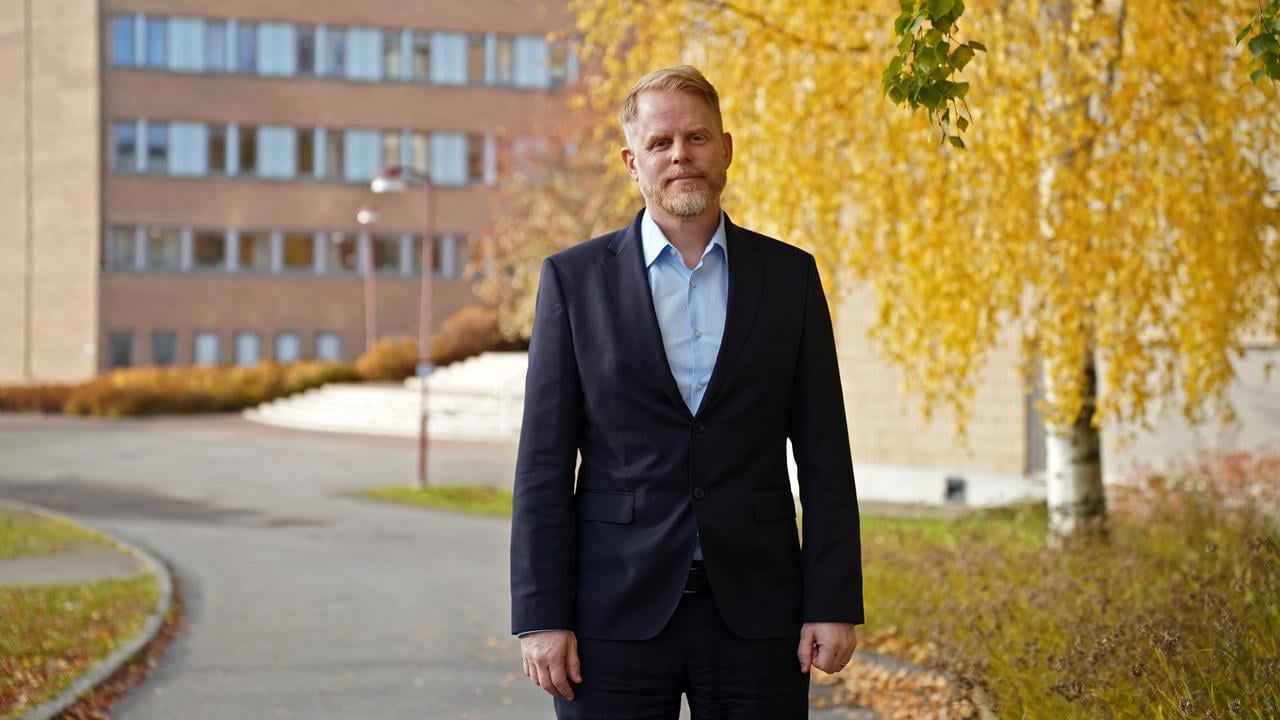 En man som st&aring;r framf&ouml;r ett tr&auml;d med gula blad.