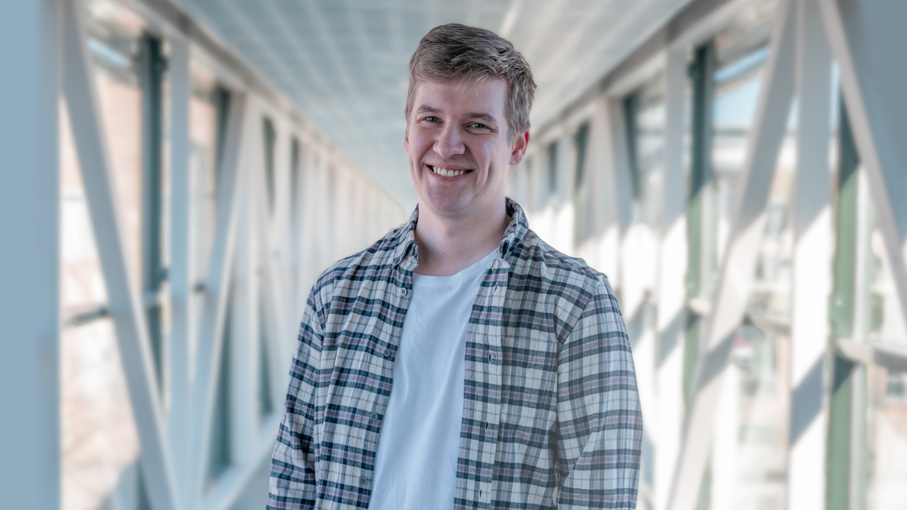 En man st&aring;r p&aring; en bro med h&auml;nderna i fickorna