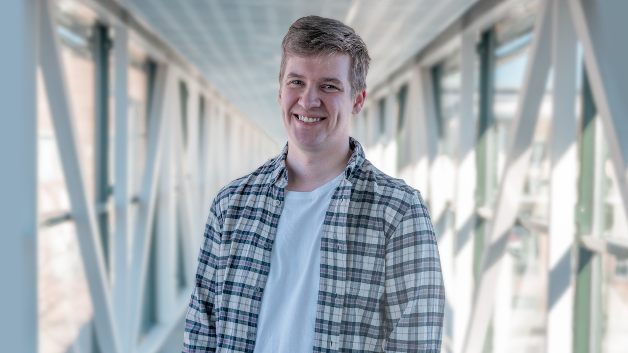 En man st&aring;r p&aring; en bro med h&auml;nderna i fickorna