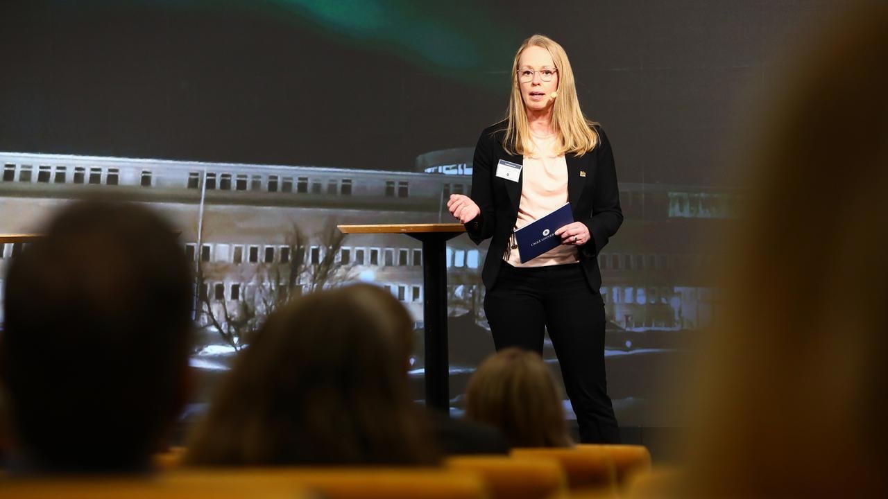 En kvinna st&aring;r p&aring; ett podium framf&ouml;r en folkmassa.