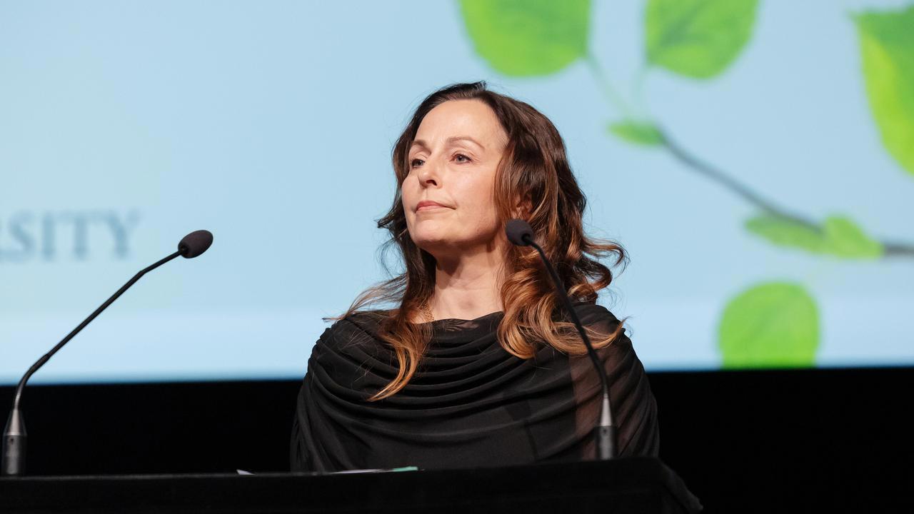 En kvinna st&aring;r p&aring; ett podium framf&ouml;r en projektionssk&auml;rm.