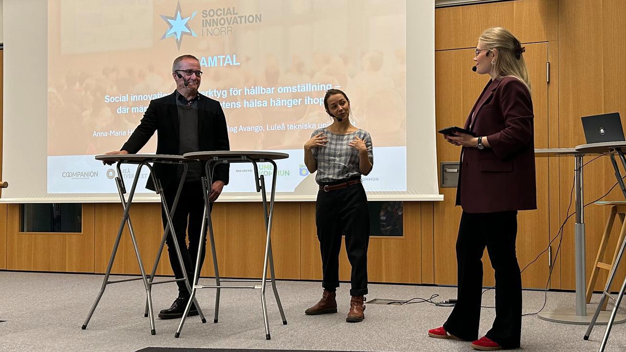 En grupp m&auml;nniskor som st&aring;r p&aring; en scen framf&ouml;r en projektorduk.