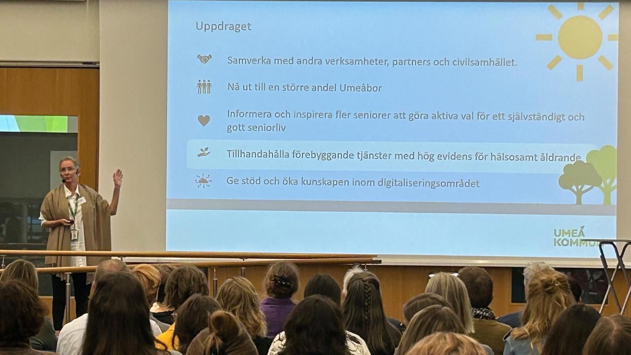 En kvinna som h&aring;ller en presentation f&ouml;r en grupp m&auml;nniskor.