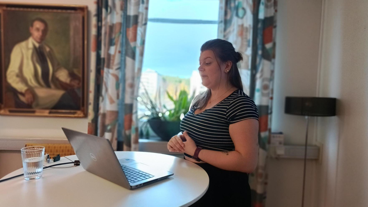 Rebecca Tapper st&aring;r vid en laptop och presenterar sitt forskningsprojekt
