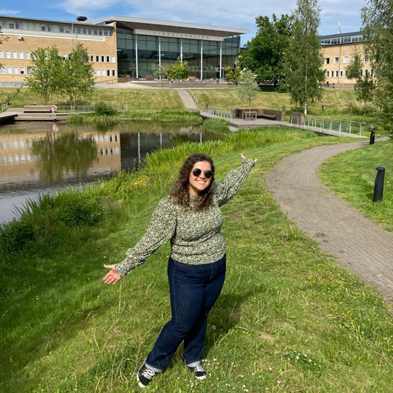 International student from Brazil posing in front of the campus pond at Ume&aring; University