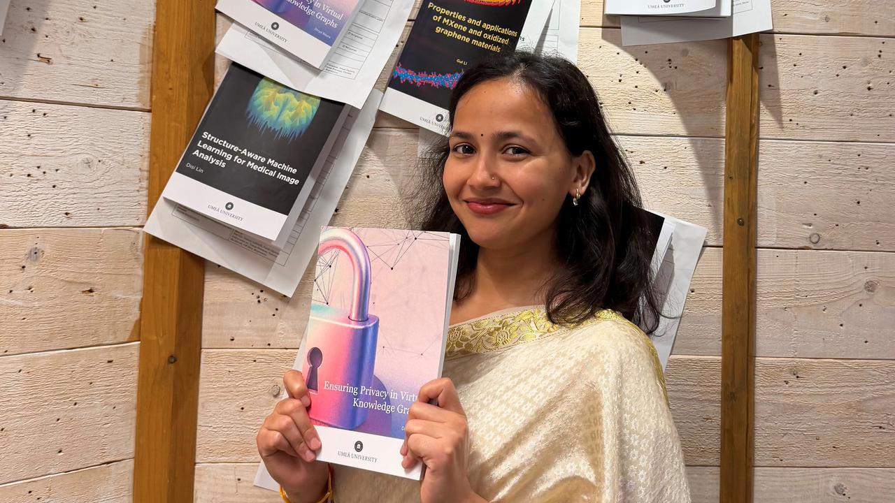 Divya Baura, i m&ouml;rkt h&aring;r och fin kl&auml;dsel, h&aring;ller upp sin avhandling under spikningsceremonin.