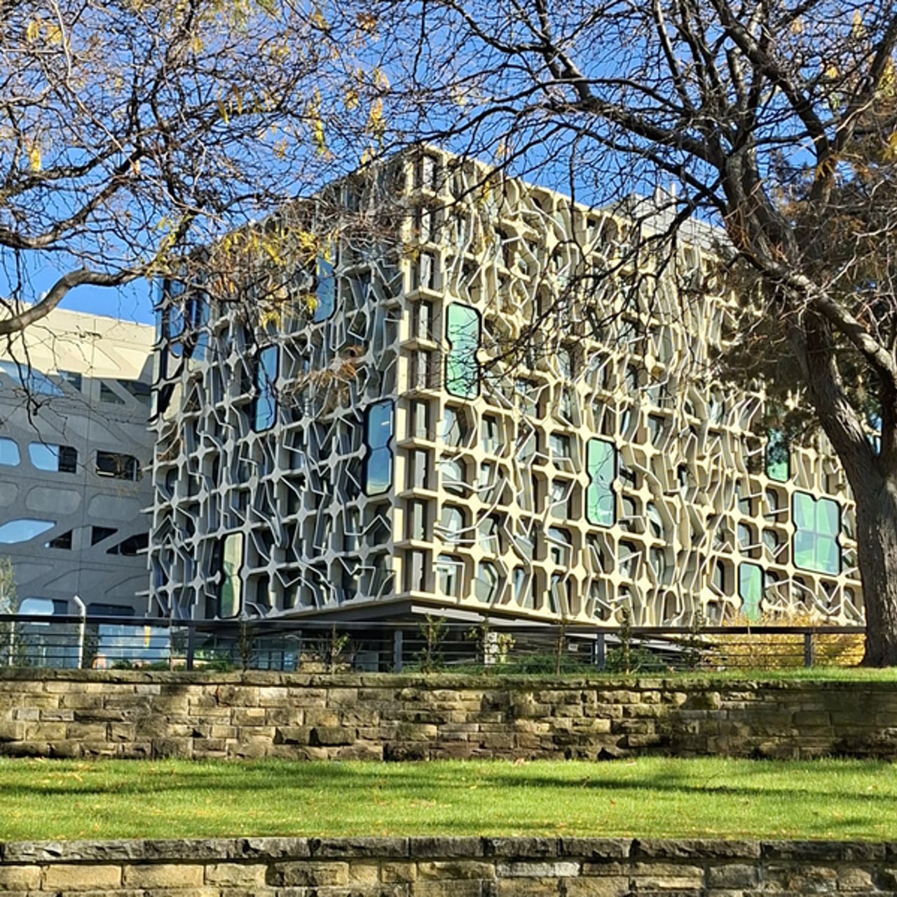 Byggnadsfasad med park i förgrunden.