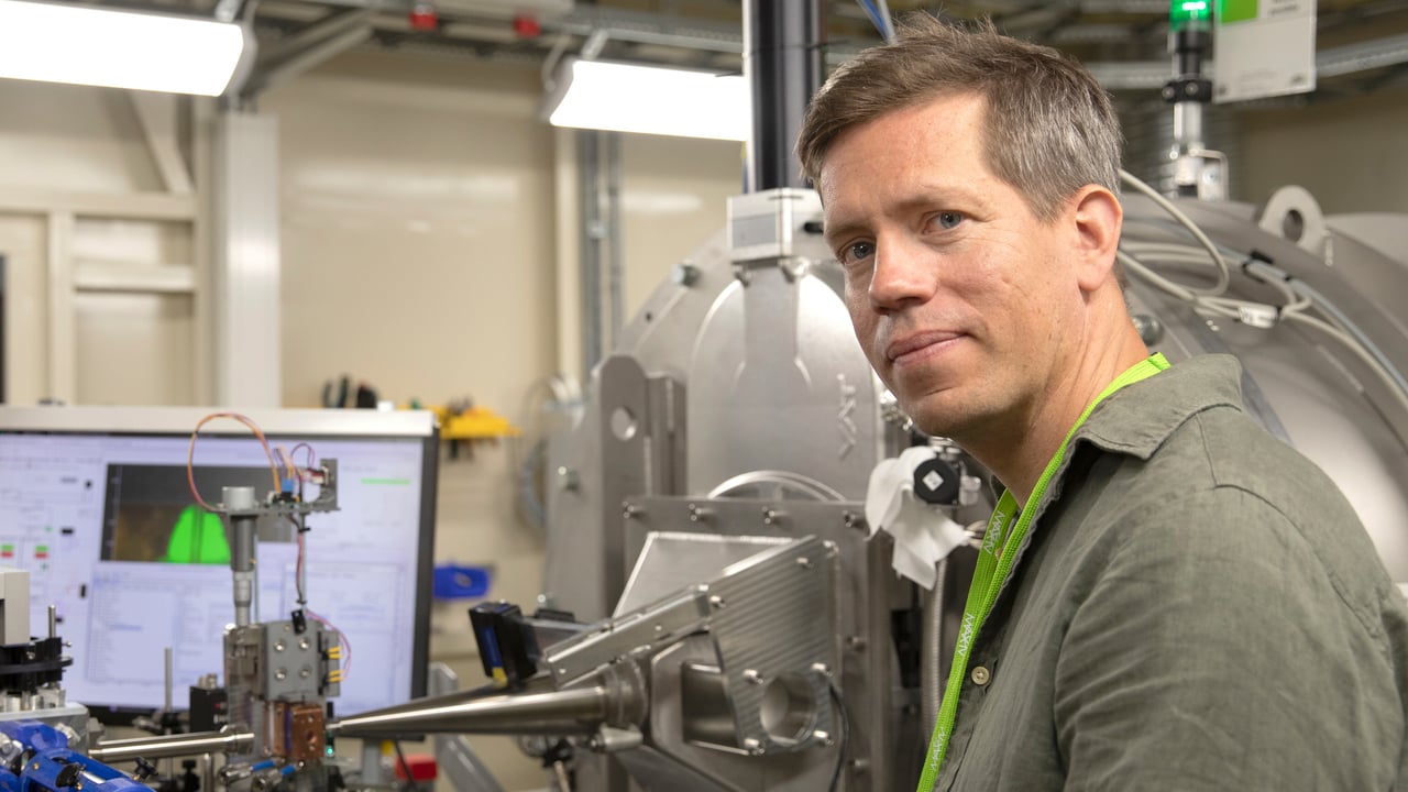 En man i halvfigur med experimentutrustning i bakgrunden.