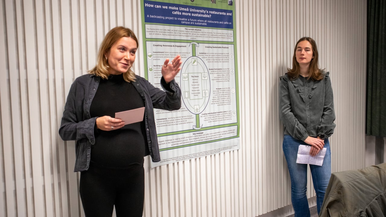 Bild p&aring; studenterna Agnes Alriksson och Rinske de Ronde st&aring;ende vid sin posterpresentation.