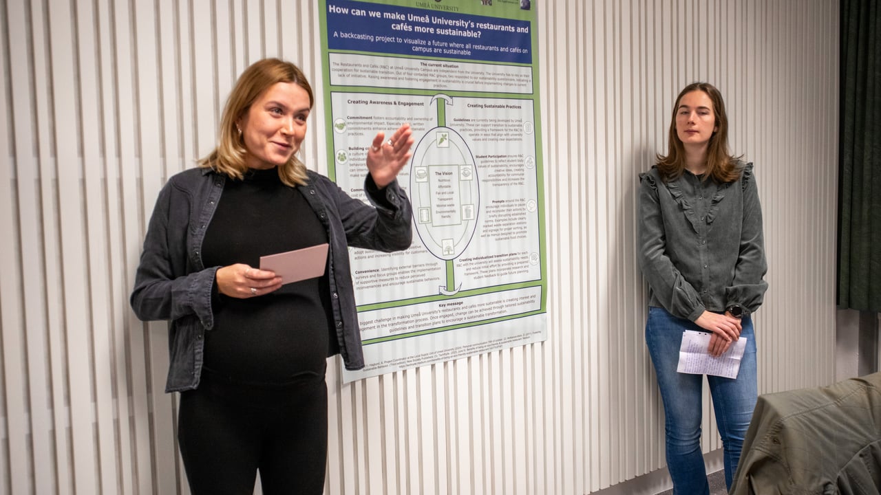 Bild p&aring; studenterna Agnes Alriksson och Rinske de Ronde st&aring;ende vid sin posterpresentation.