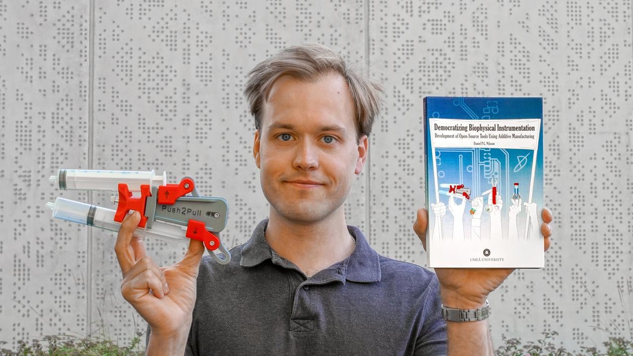En man som h&aring;ller upp en bok och ett forskningsinstrument.