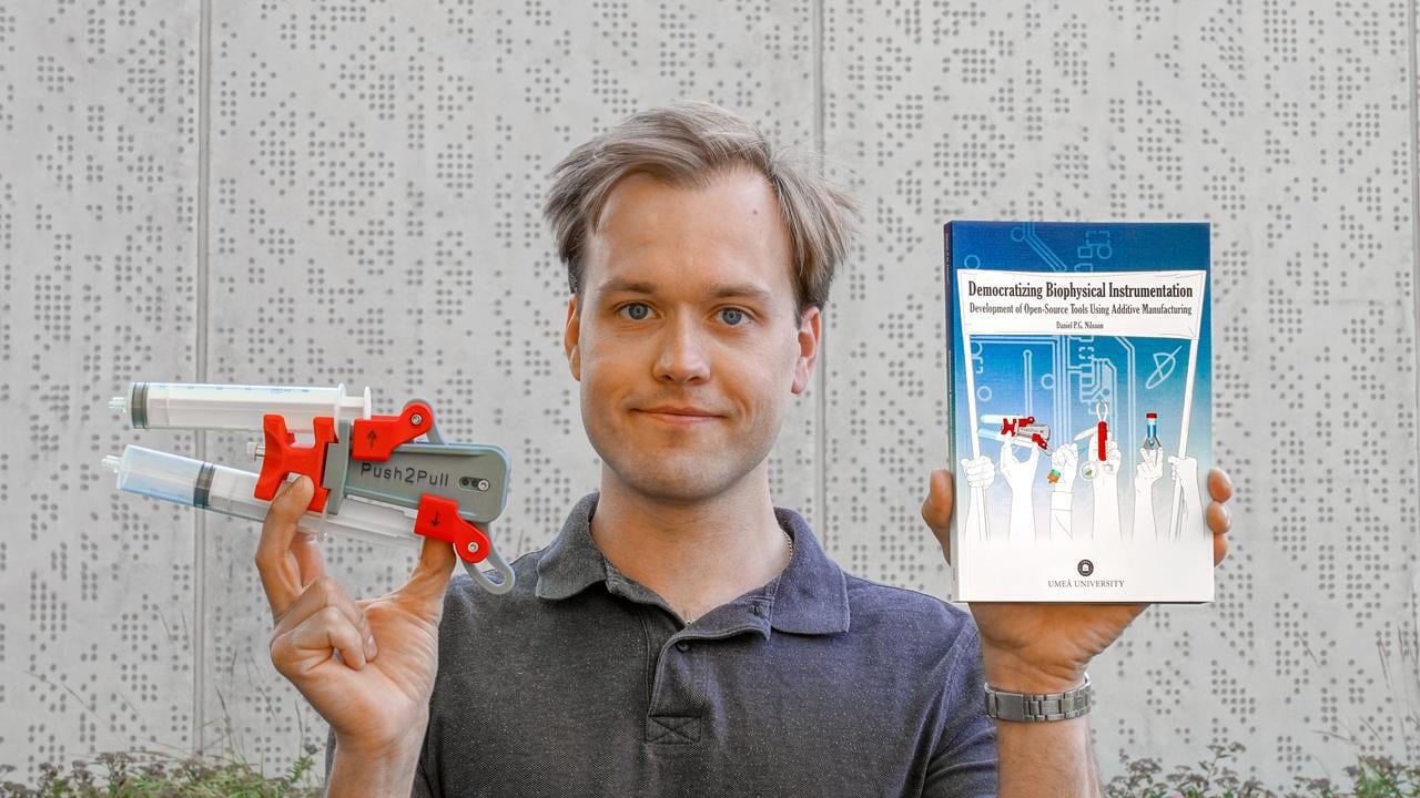 En man som håller upp en bok och ett forskningsinstrument.