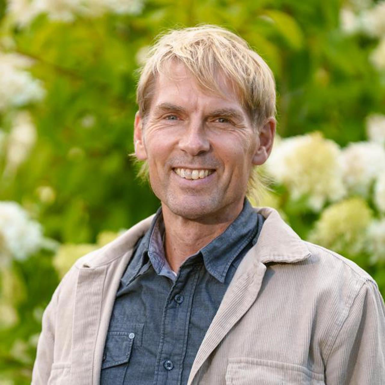 Man som st&aring;r utomhus framf&ouml;r en blommande buske