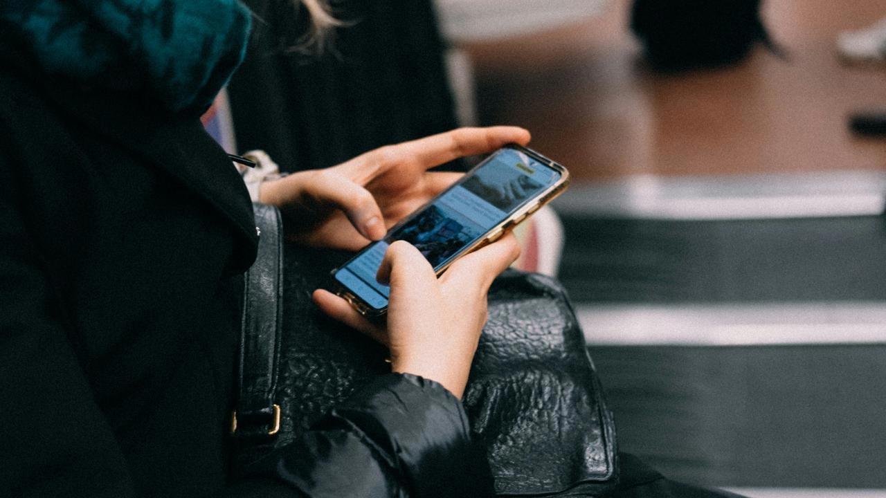 En person som sitter p&aring; en b&auml;nk och pratar i mobiltelefon.