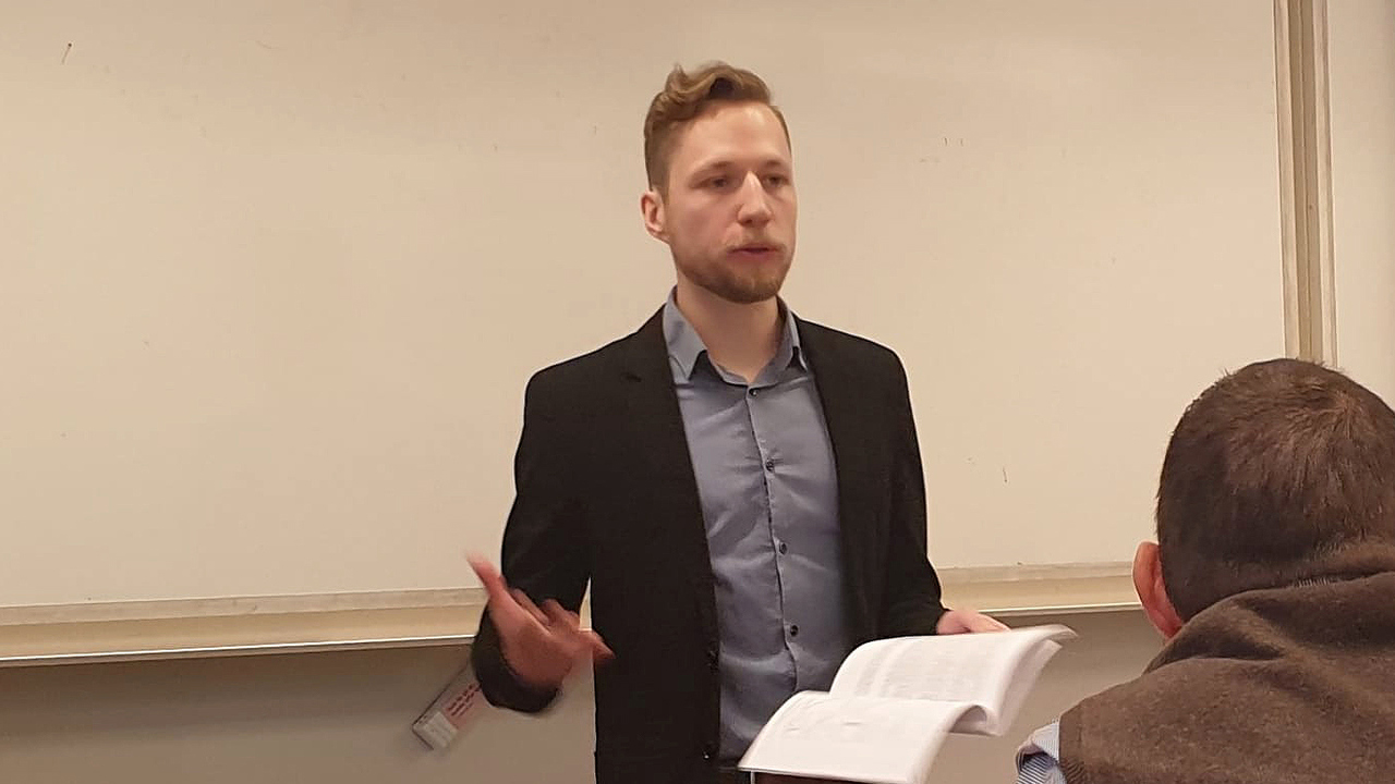 Micka&euml;l Zehren st&aring;r i svart kavaj och f&ouml;rsvarar sin avhandling.