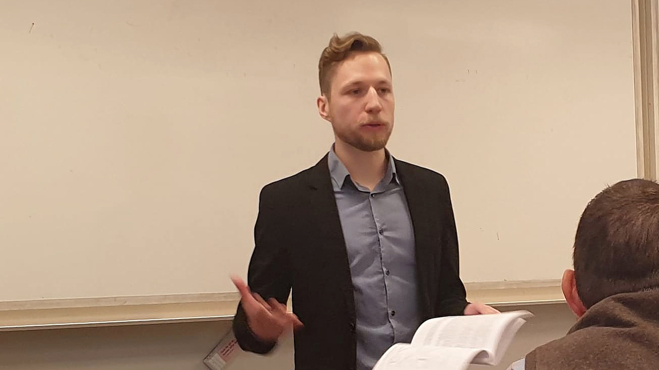 Micka&euml;l Zehren st&aring;r i svart kavaj och f&ouml;rsvarar sin avhandling.