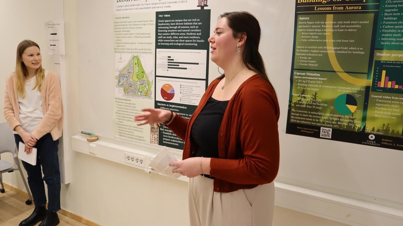 Bild p&aring; studenterna Nadine Peels och Jenny Ojala, st&aring;ende vid posters under redovisning av projekt.