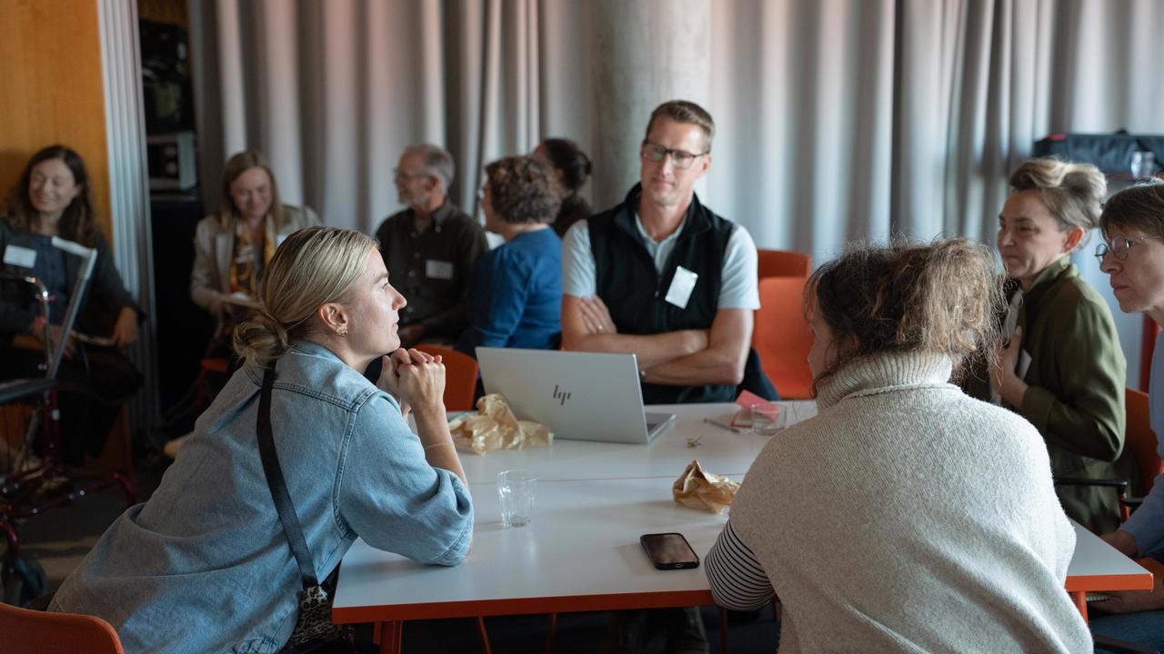 Personer sitter runt ett bord och diskuterar.