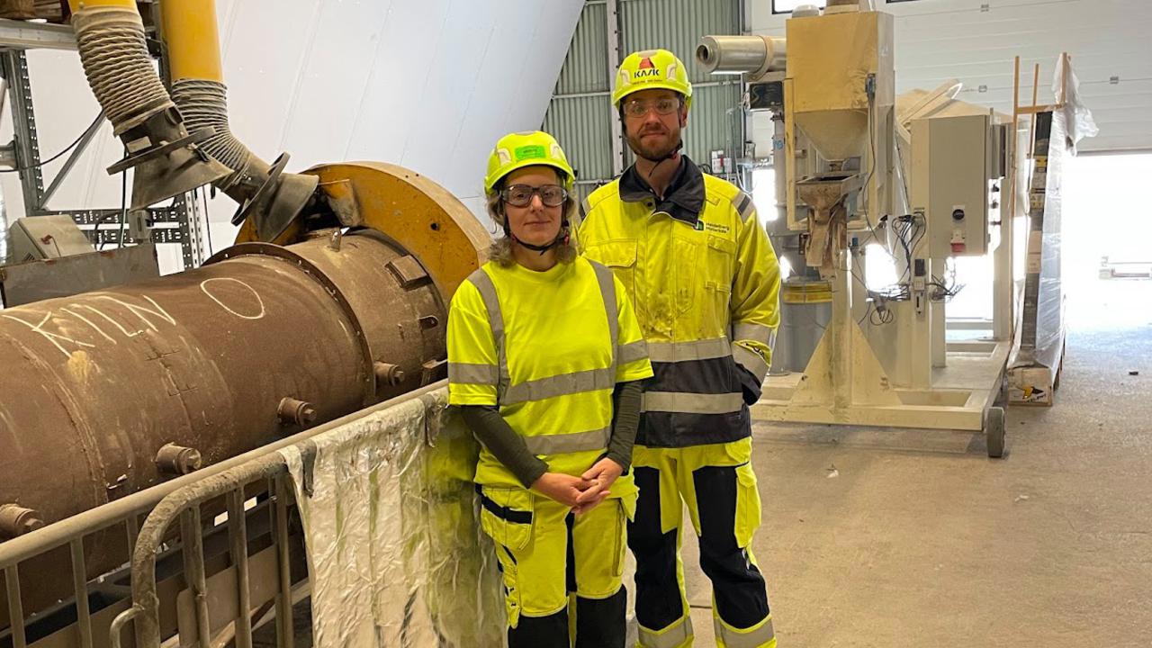 Två personer i varselkläder vid en cementugn.
