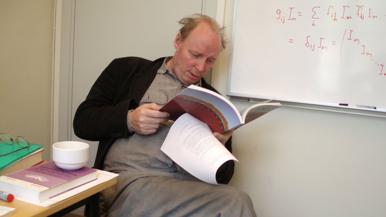 Bild av professor Roland H&auml;ggkvist som sitter p&aring; en stol och l&auml;ser en tidsskrift