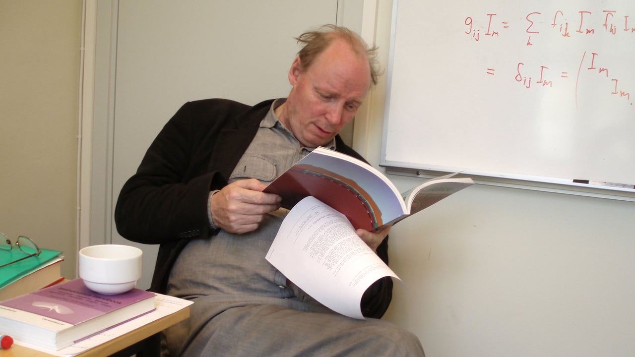 Bild av professor Roland H&auml;ggkvist som sitter p&aring; en stol och l&auml;ser en tidsskrift