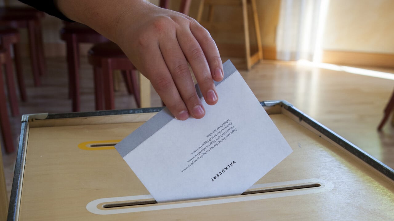 Hand som l&auml;gger ett valkuvert i valurnan i en r&ouml;stlokal.