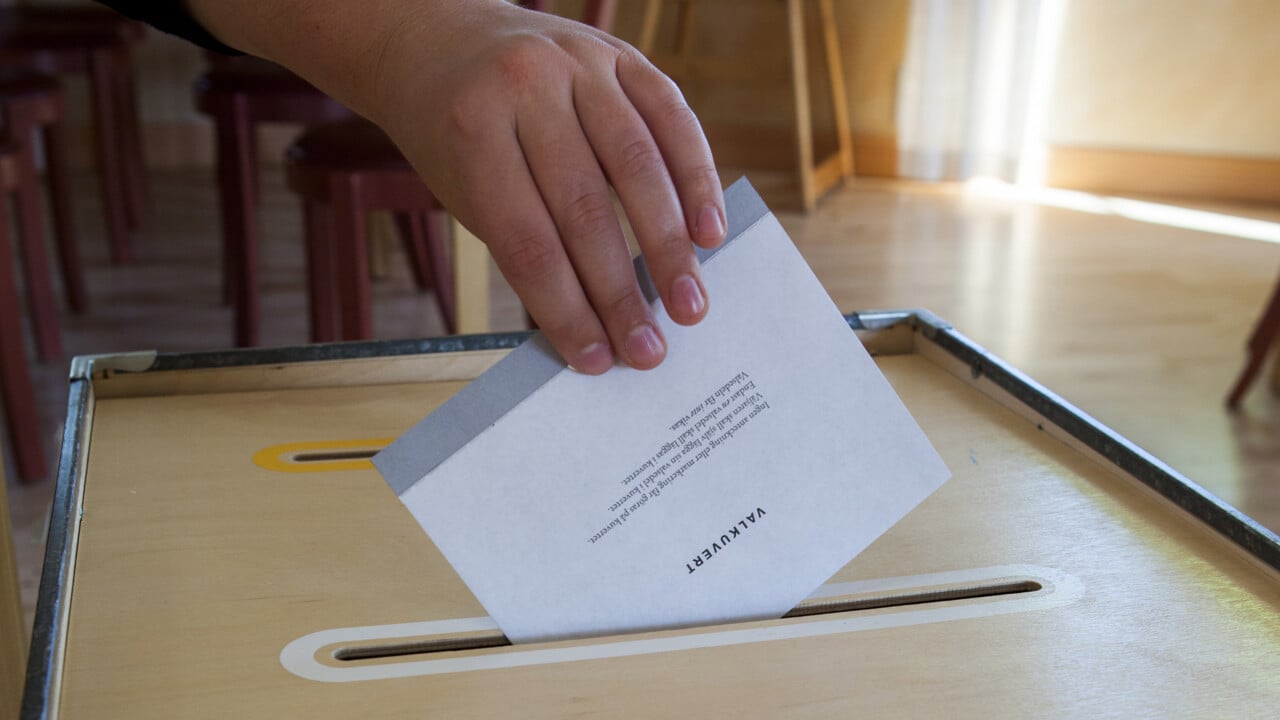 Hand som l&auml;gger ett valkuvert i valurnan i en r&ouml;stlokal.