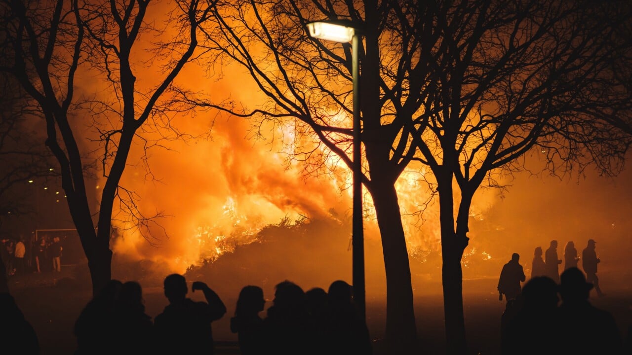 Flammor fr&aring;n intensiv skogsbrand med m&auml;nskliga silhuetter i f&ouml;rgrunden