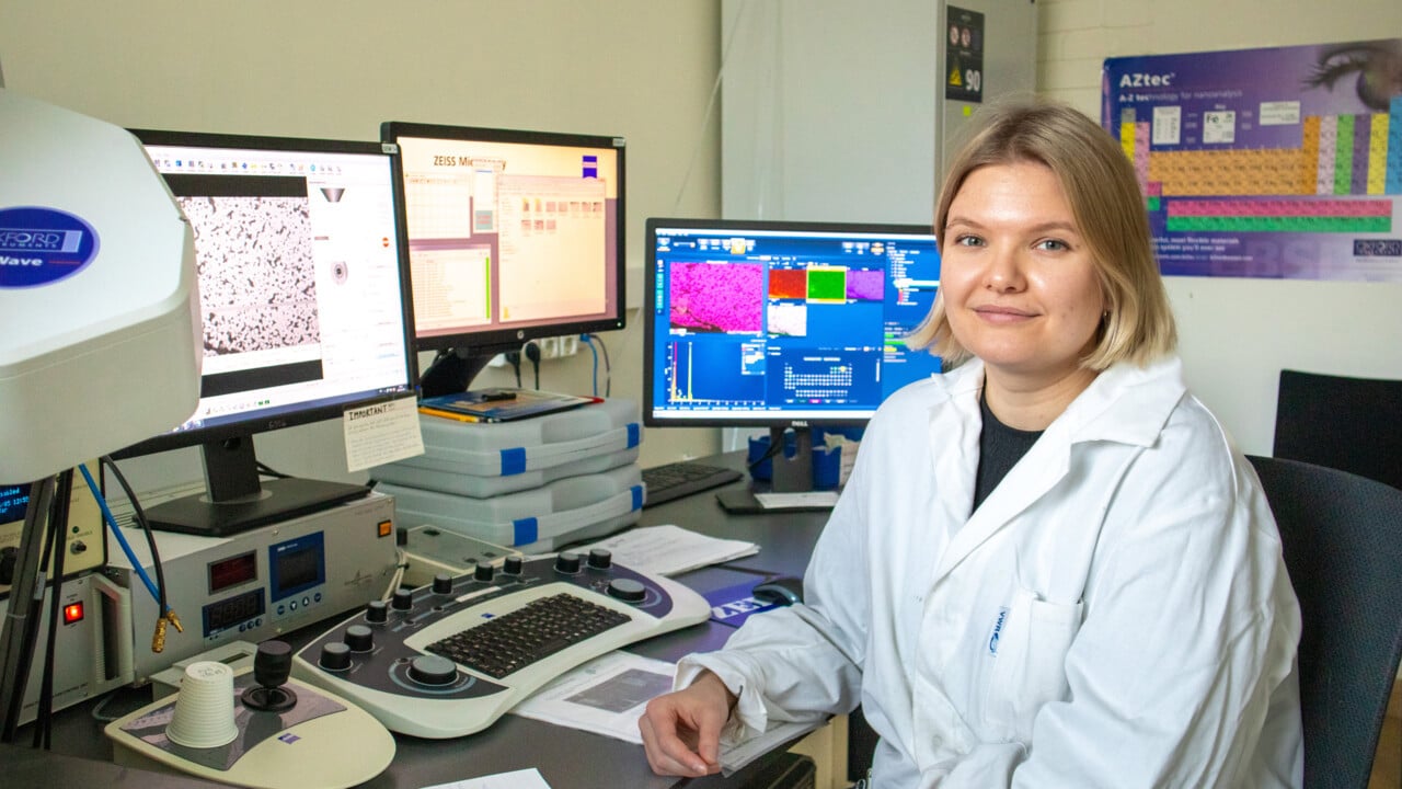 Kvinna i vit labbrock vid datorsk&auml;rmar.
