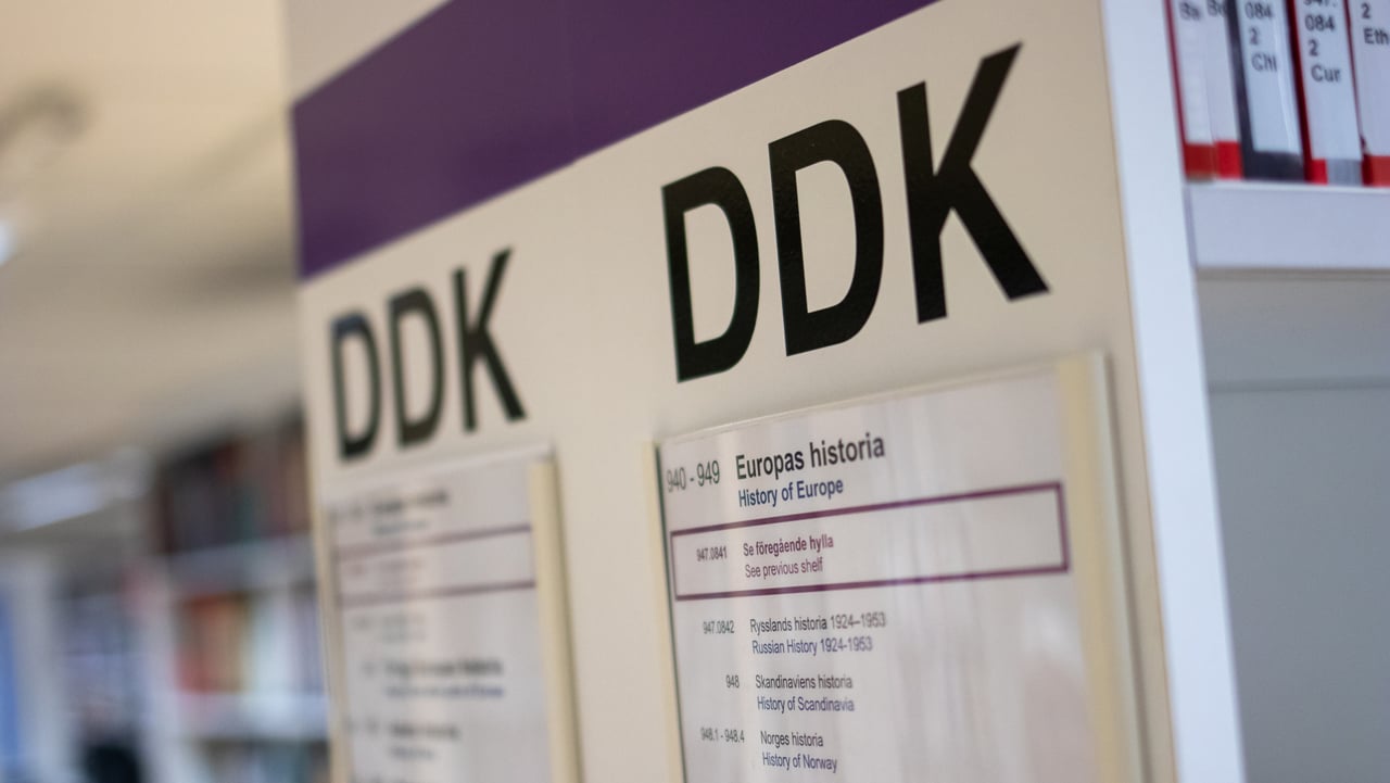 DDK-skylt p&aring; en av bibliotekets hyllgavlar