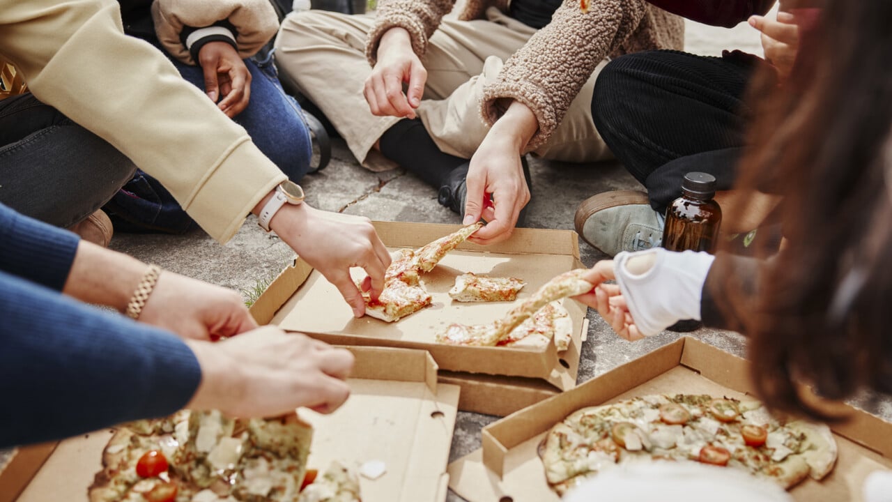 N&auml;rbild p&aring; h&auml;nder som str&auml;cker sig efter pizza.
