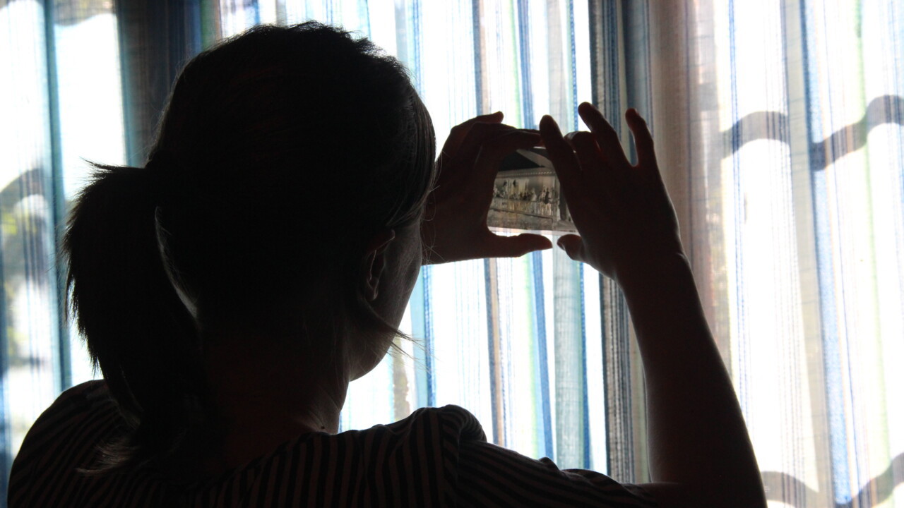 Jenny Ingridsdotter ute hos informant fotograferar ut ur ett f&ouml;nster och bilden &auml;r tagen i motljus.