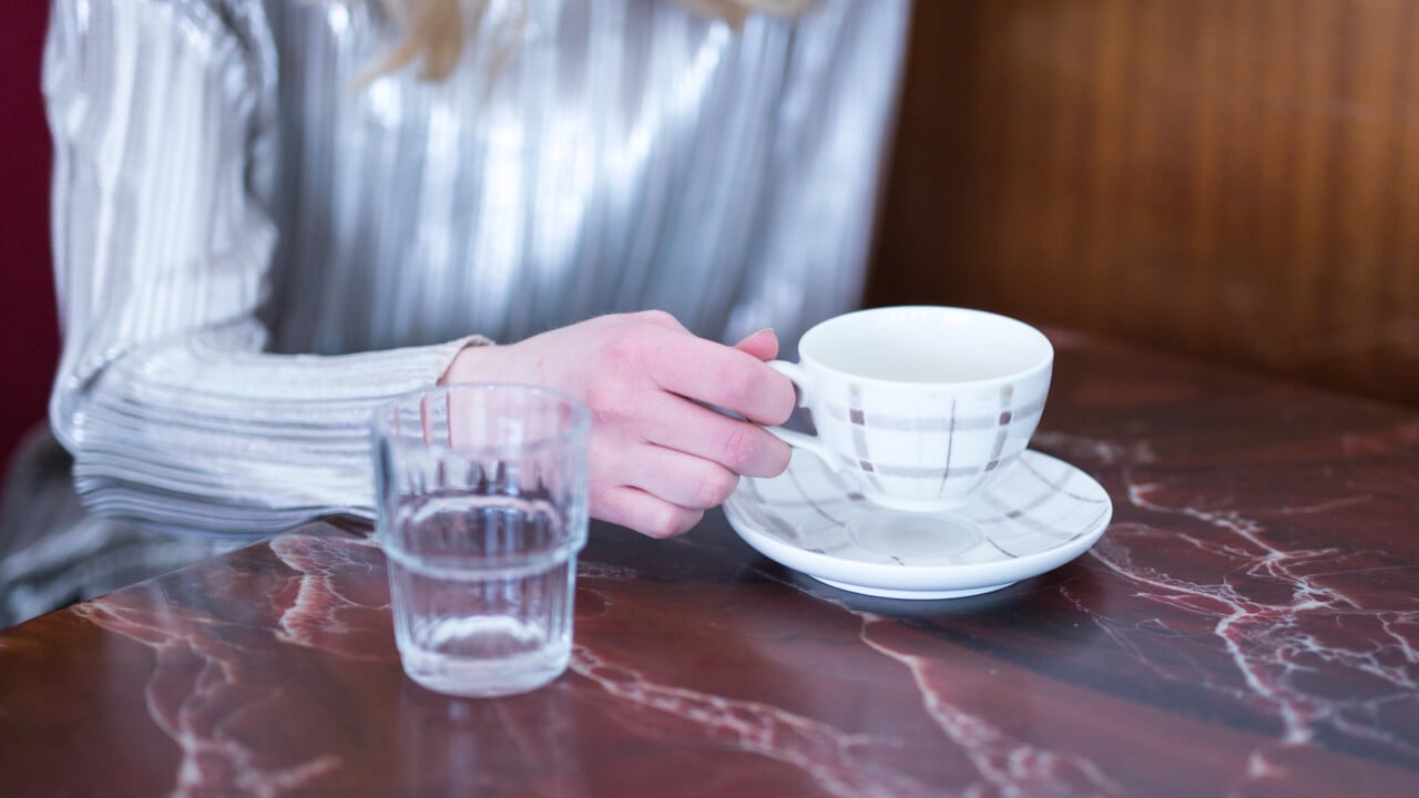 Detalj p&aring; person med kaffekopp p&aring; ett caf&eacute;.