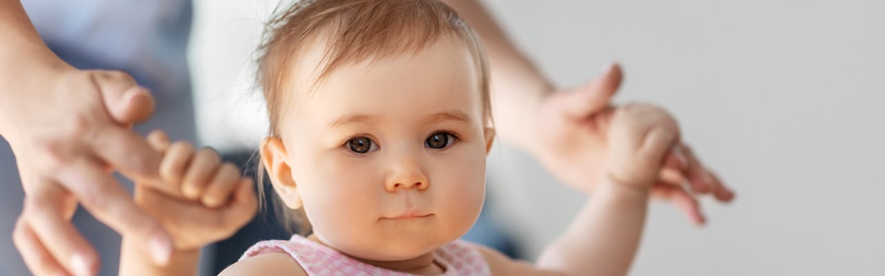Liten flicka lär sig gå med hjälp av sin mamma.
