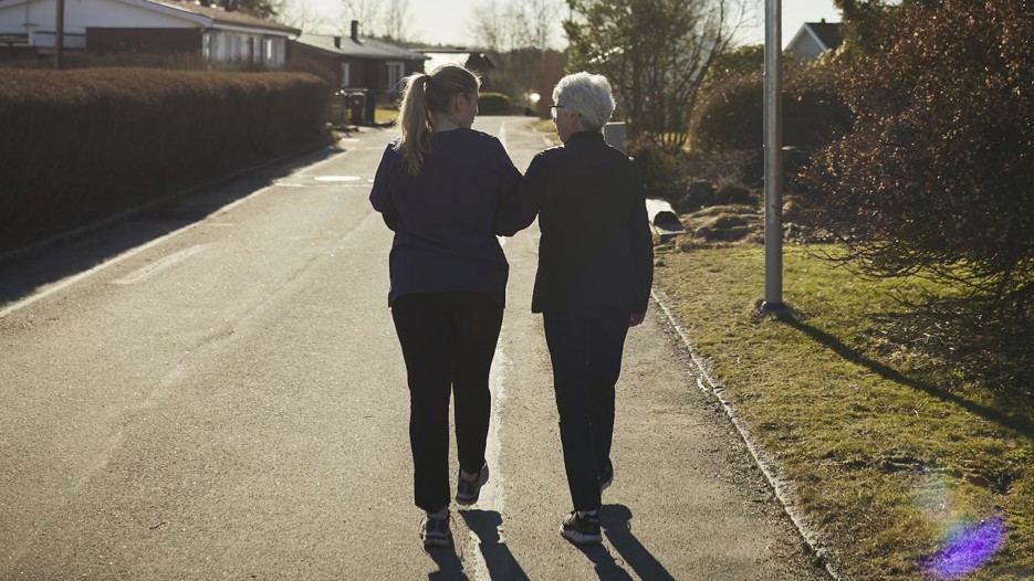 Äldre och yngre kvinna promenerar bort från fotografen
