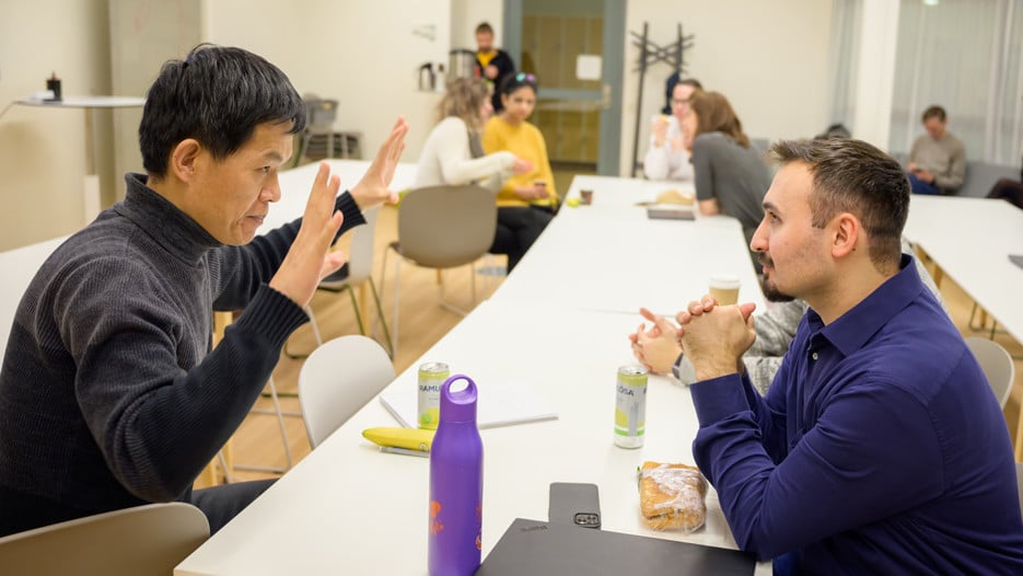 Jian-Feng Mao and Cemal Erdem sit across from each other at a white table and discuss.