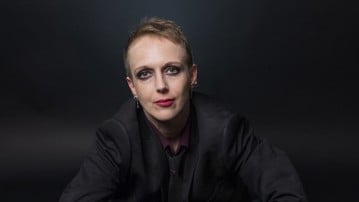 Sofia Jeppsson, porträttfoto sittande på marken iklädd svart kostym. 