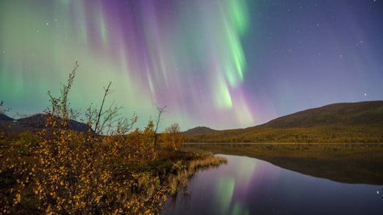 Northern lights in the sky over mountain lake landscape