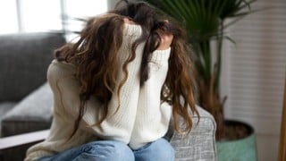 Kvinna som döljer sitt ansikte i sina händer. Ska illustrera psykisk ohälsa, ångest, oro, stress, depression, nedstämdhet eller liknande.