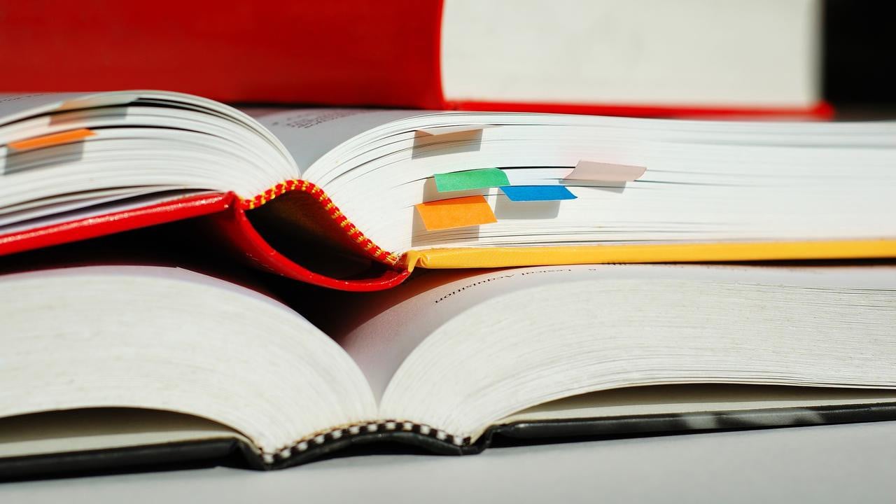 Books are piled with bookmarks. Genrebild från Mostphotos.