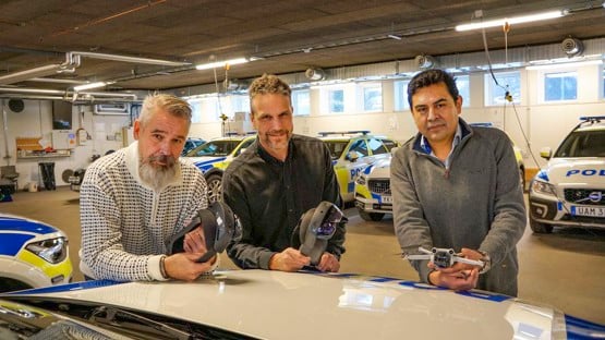 Tre personer står med Holo Lens och drönare vid en polisbil. Det är Anders Schogster och Jonas Hansson från enheten för polisutbildningen och Juan Carlos Nieves Sanchez, universitetslektor i datavetenskap.