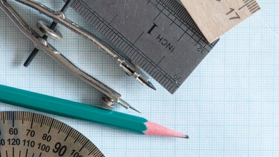 Uppsättning med rit- och mätinstrument och penna på rutat papper.