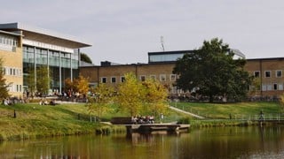 Studenter utomhus på campus. Vy över dammen och Lindellhallen. Bilden har formatet 16x9 och är anpassad för att användas som toppbild på studentrekryteringswebben.